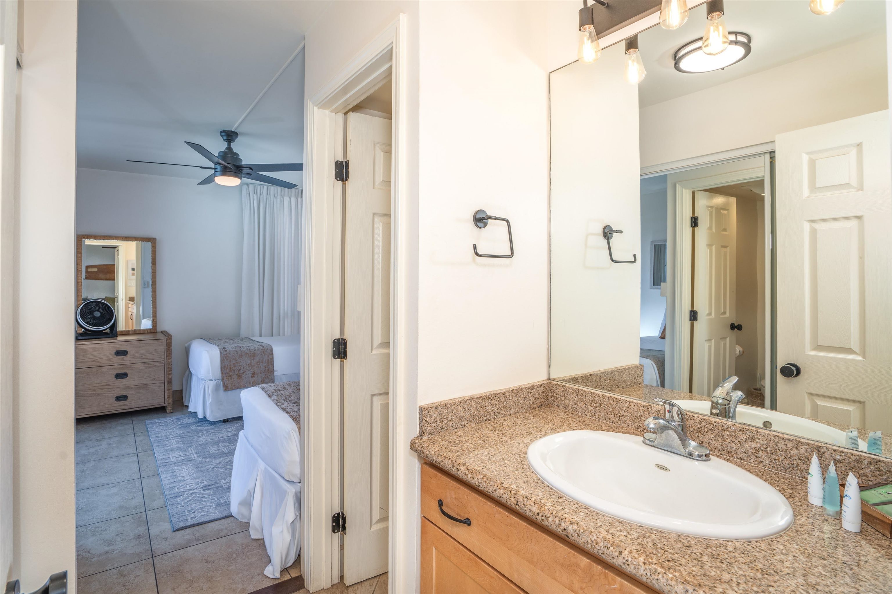 2450 South Kihei Road, Unit 301 Kihei, HI 96753 - Photo 25 of 35 a bathroom with a granite countertop sink a mirror and a toilet
