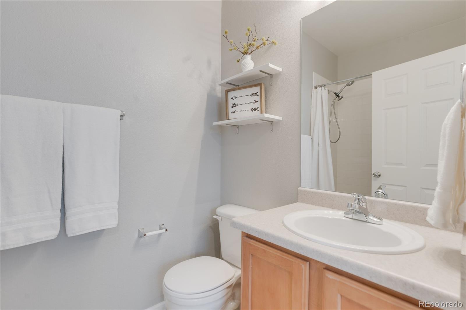 5392 Allison Street Arvada, CO 80002 - Photo 23 of 47 a bathroom with a granite countertop sink a toilet and a mirror