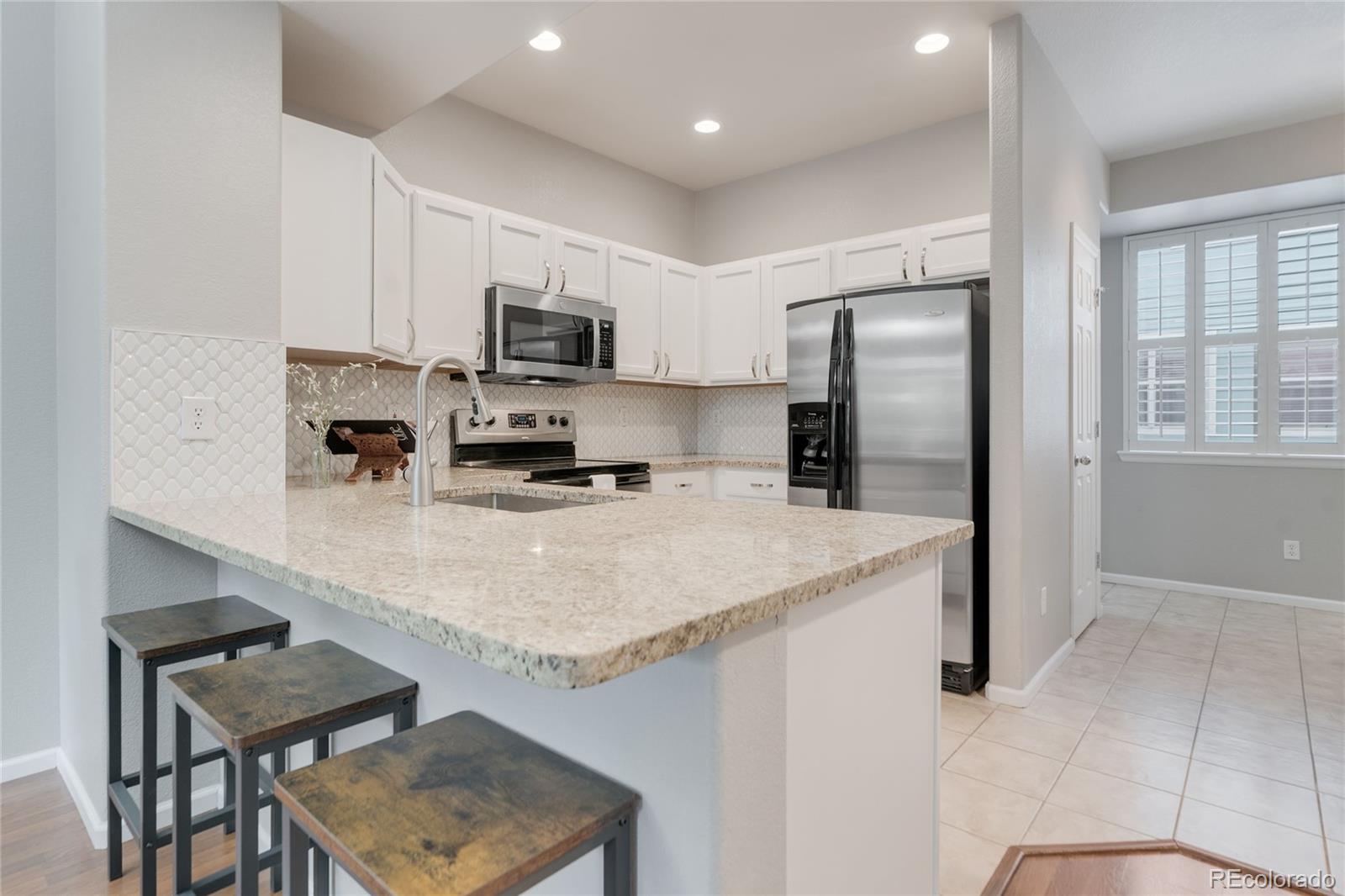 5392 Allison Street Arvada, CO 80002 - Photo 3 of 47 a kitchen with kitchen island a refrigerator stove and microwave
