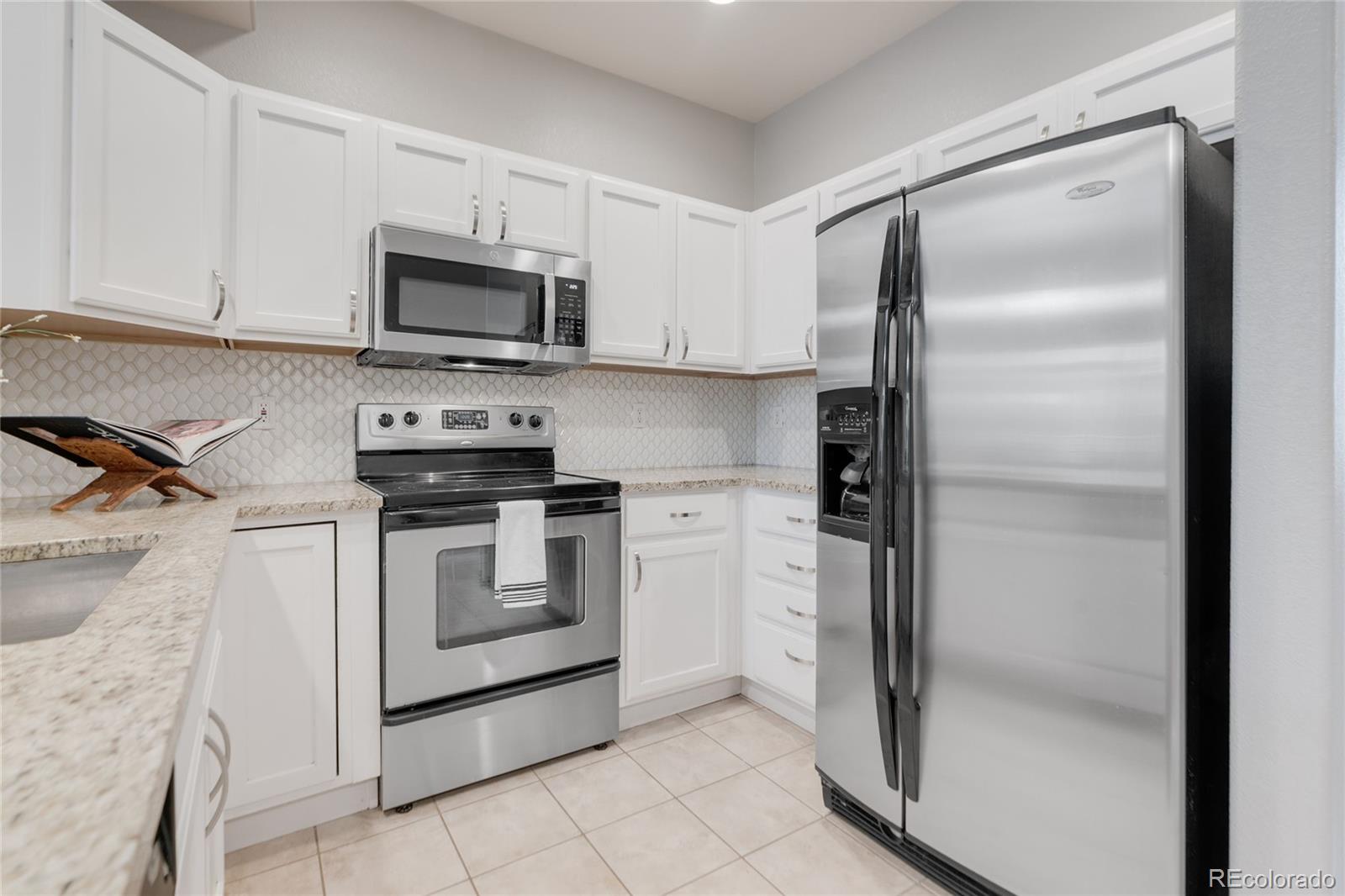 5392 Allison Street Arvada, CO 80002 - Photo 4 of 47 a kitchen with white cabinets and stainless steel appliances