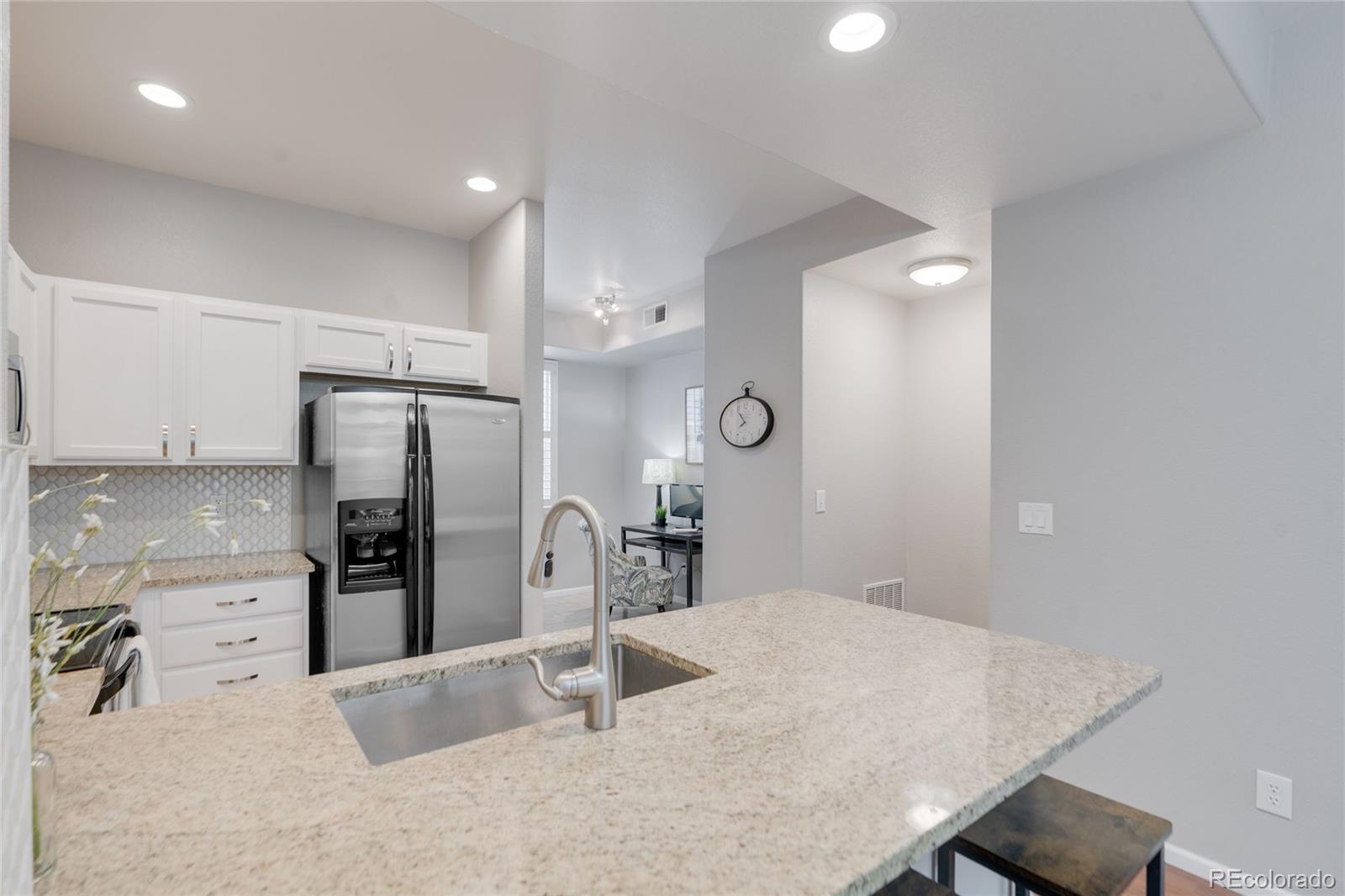 5392 Allison Street Arvada, CO 80002 - Photo 6 of 47 a kitchen with stainless steel appliances kitchen island granite countertop a refrigerator and stove