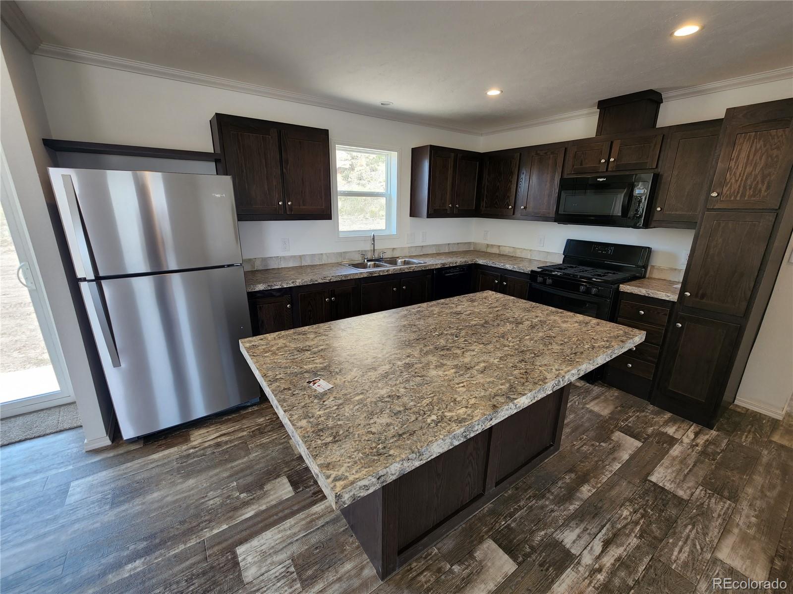 207 Willow Street Rockvale, CO 81244 - Photo 8 of 19 a kitchen with stainless steel appliances granite countertop a refrigerator a stove a sink and a microwave