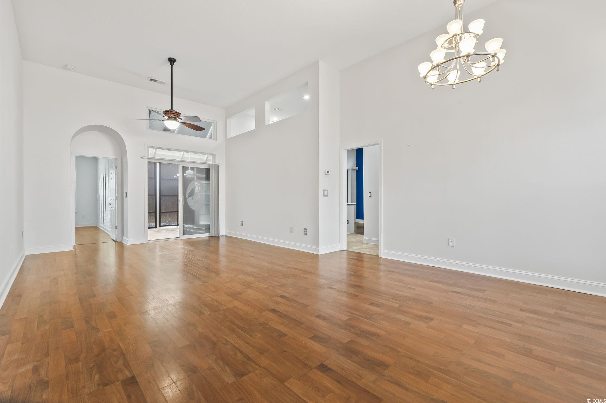 743 Helms Way Conway, SC 29526 - Photo 2 of 37 Unfurnished living room with wood finished floors, a towering ceiling, a chandelier, a ceiling fan, and arched walkways