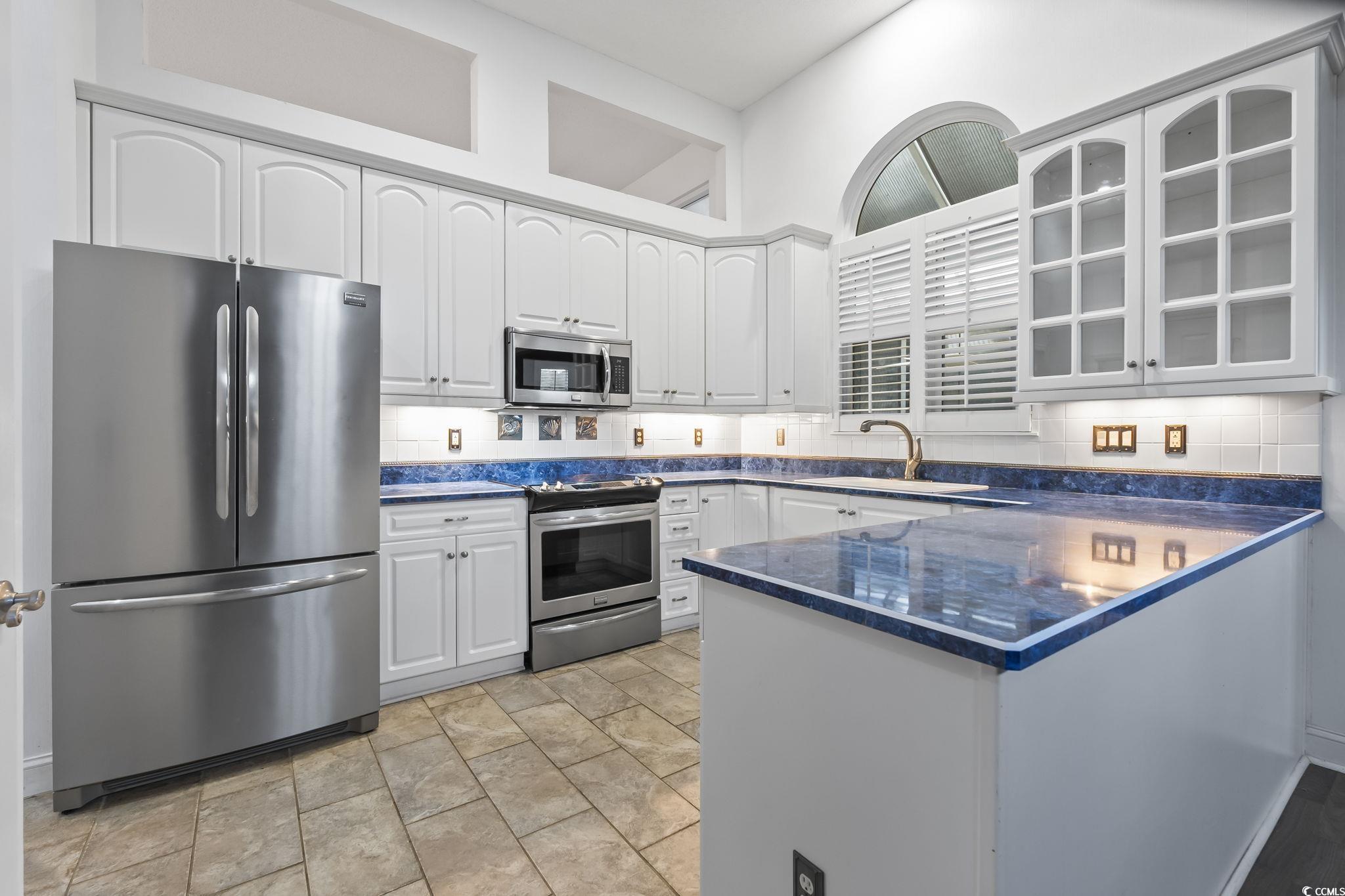 743 Helms Way Conway, SC 29526 - Photo 3 of 37 Kitchen featuring stainless steel appliances, decorative backsplash, a peninsula, dark stone countertops, and glass insert cabinets
