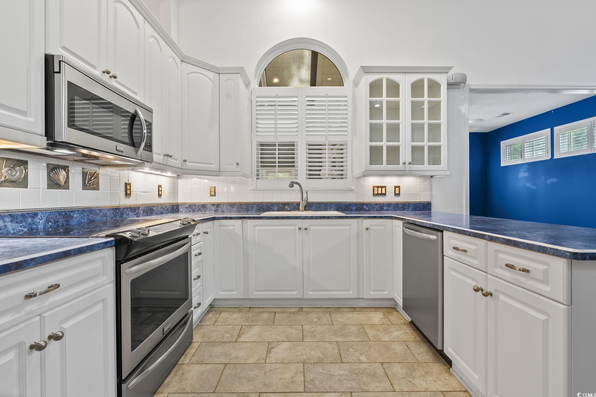743 Helms Way Conway, SC 29526 - Photo 10 of 37 Kitchen with appliances with stainless steel finishes, white cabinetry, backsplash, glass insert cabinets, and a peninsula