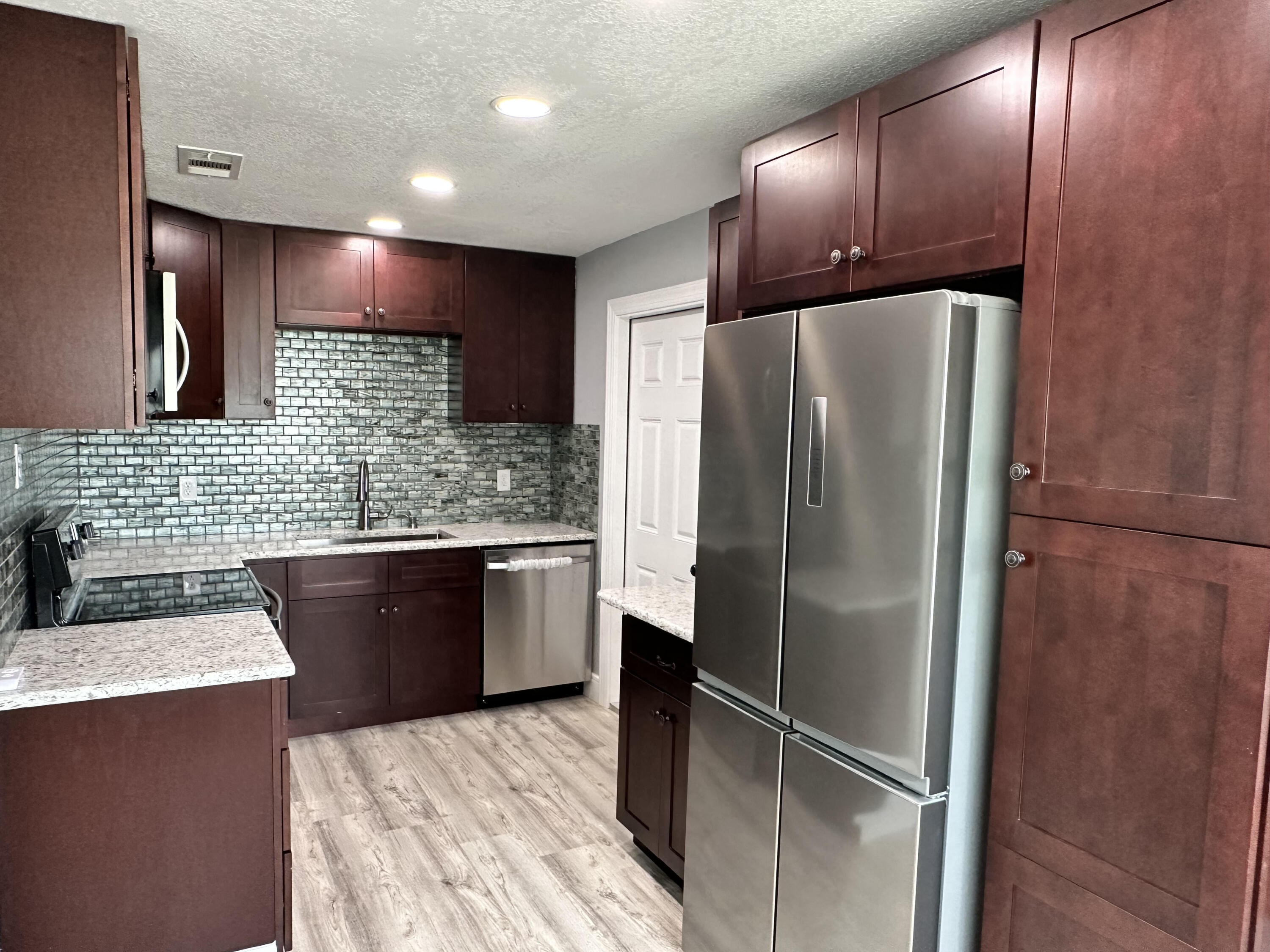 2814 Southeast Indian Street Stuart, FL 34997 - Photo 4 of 23 a kitchen with granite countertop stainless steel appliances a refrigerator and cabinets