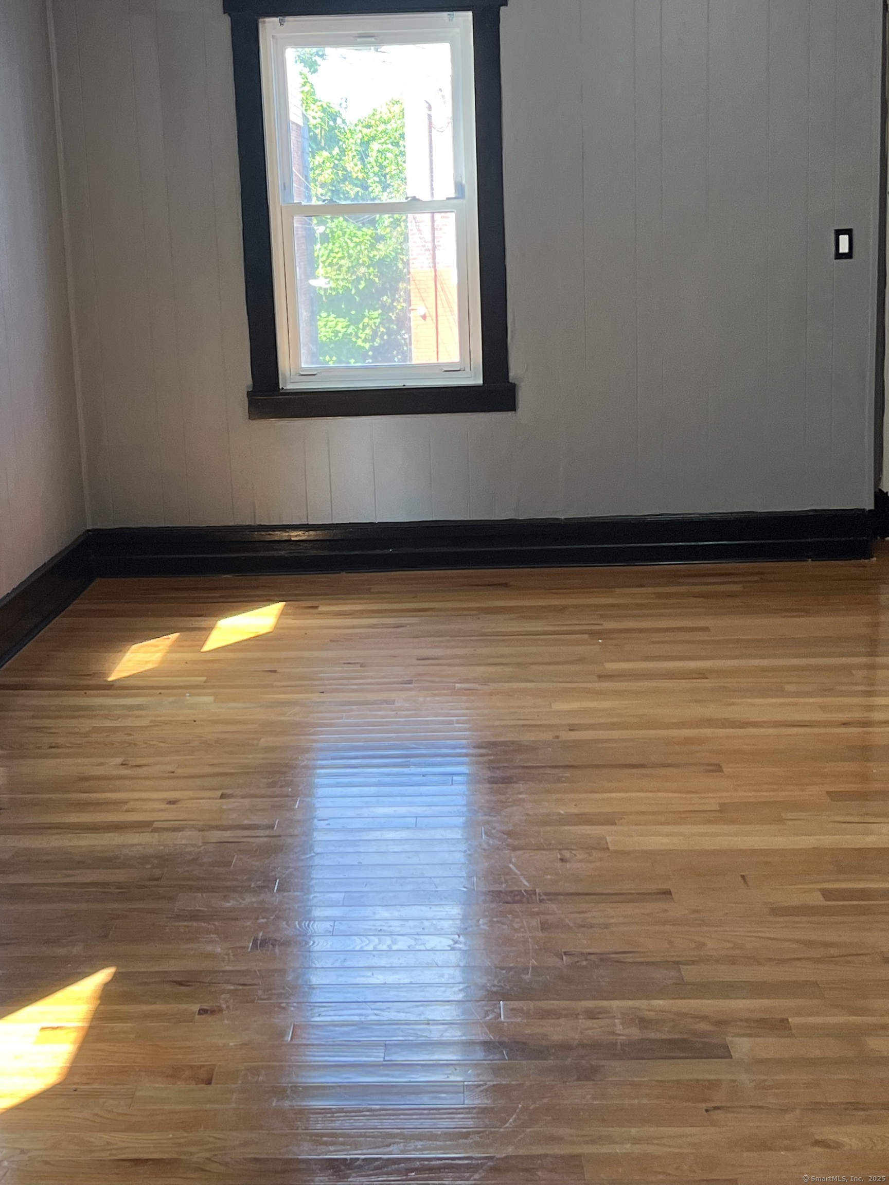 a view of empty room with window and wooden floor