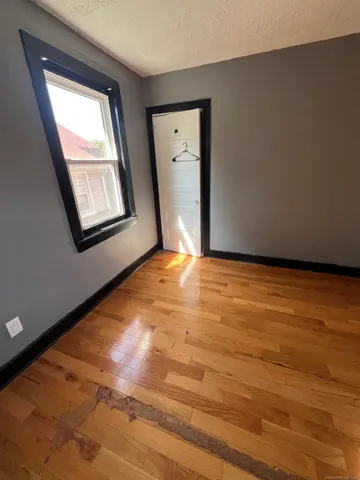 a view of an empty room with window and wooden floor