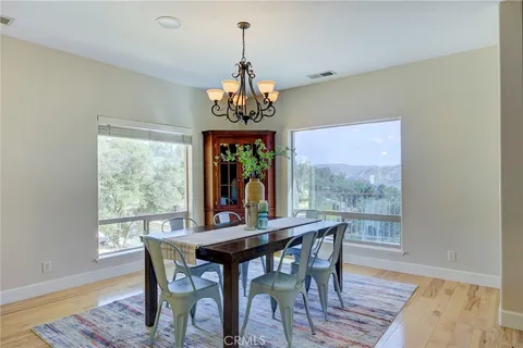 a dining room with wooden floor a chandelier a wooden table and chairs