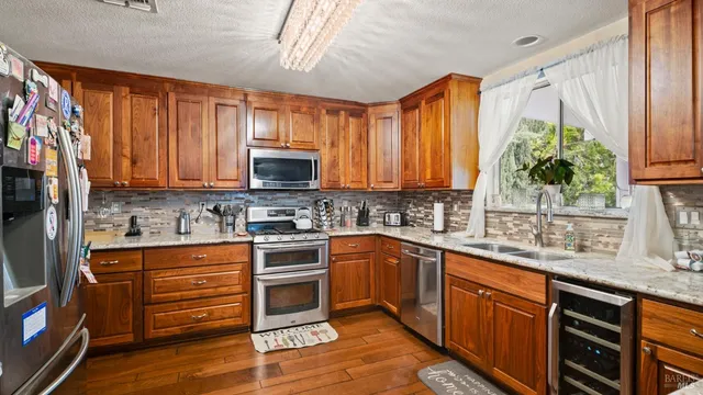 a kitchen with stainless steel appliances granite countertop wooden cabinets a sink and dishwasher with wooden floor