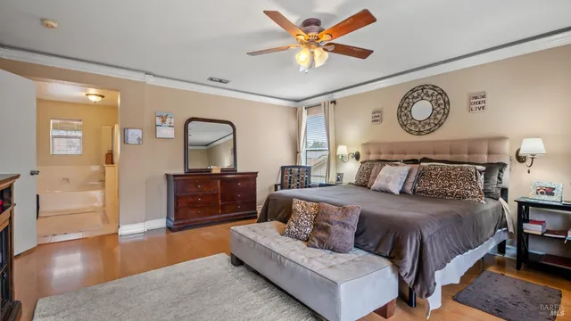 a bedroom with a bed and dresser with wooden floor