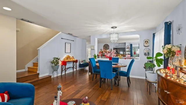 a living room with furniture and a dining table with wooden floor