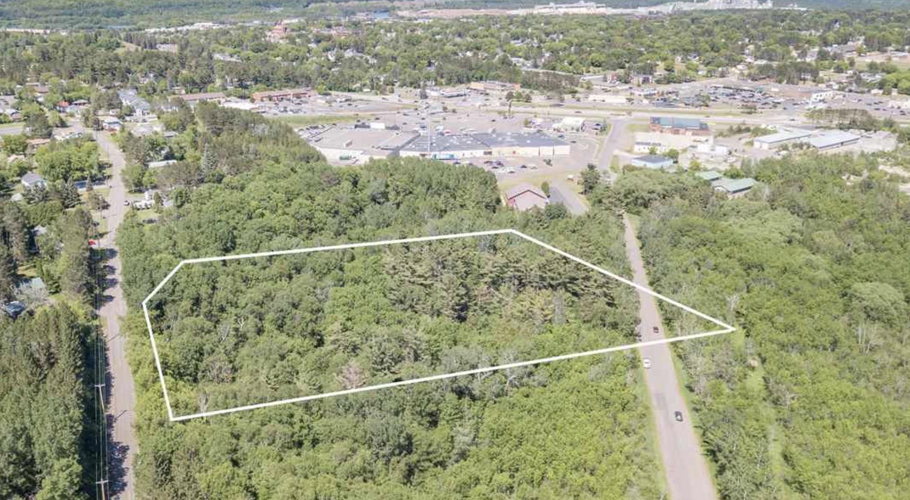 Aerial view of property and surrounding area with a heavily wooded area and property boundaries highlighted