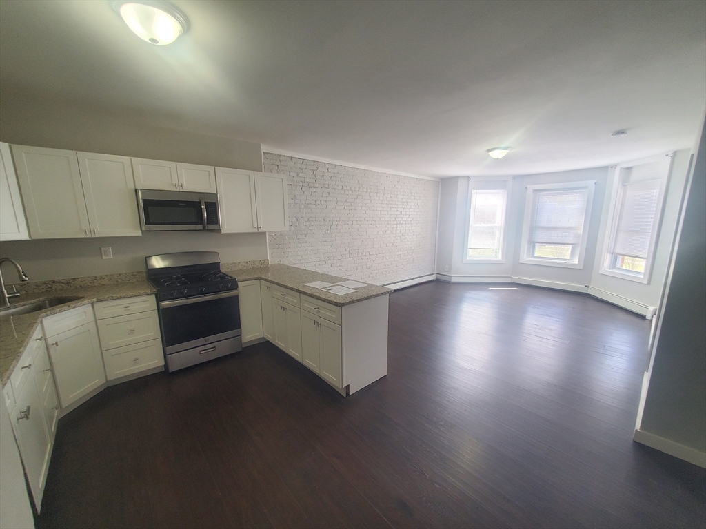 620 Dudley Street, Unit 4 Boston, MA 02125 - Photo 1 of 14 a kitchen with granite countertop white cabinets and white appliances