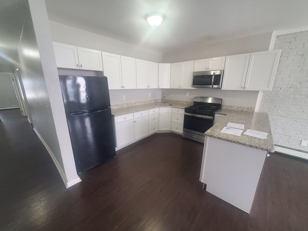 620 Dudley Street, Unit 4 Boston, MA 02125 - Photo 3 of 14 a kitchen with stainless steel appliances a refrigerator stove microwave and sink
