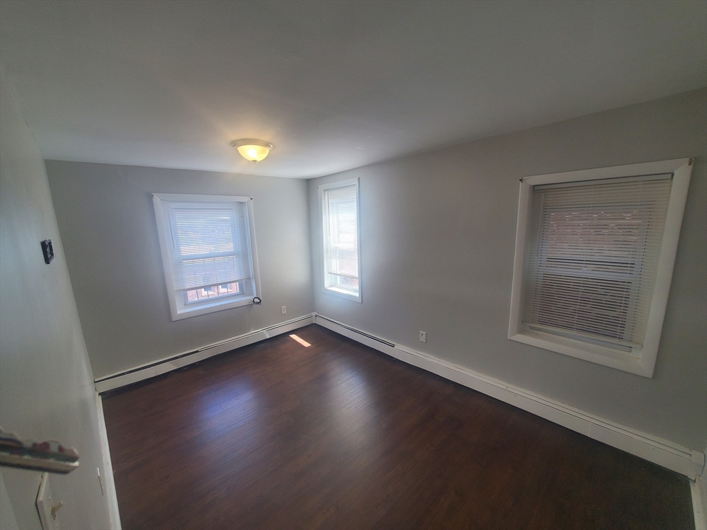620 Dudley Street, Unit 4 Boston, MA 02125 - Photo 4 of 14 a view of an empty room with a window and wooden floor