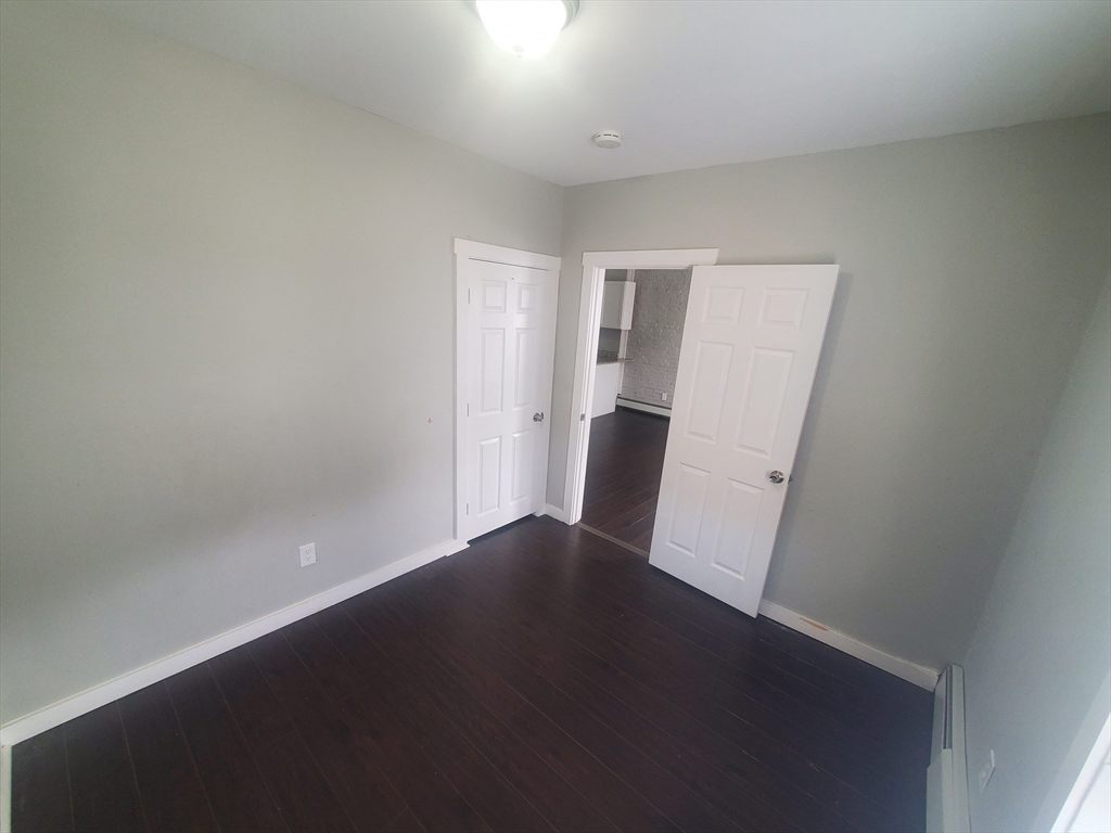 620 Dudley Street, Unit 4 Boston, MA 02125 - Photo 9 of 14 an empty room with wooden floor and windows