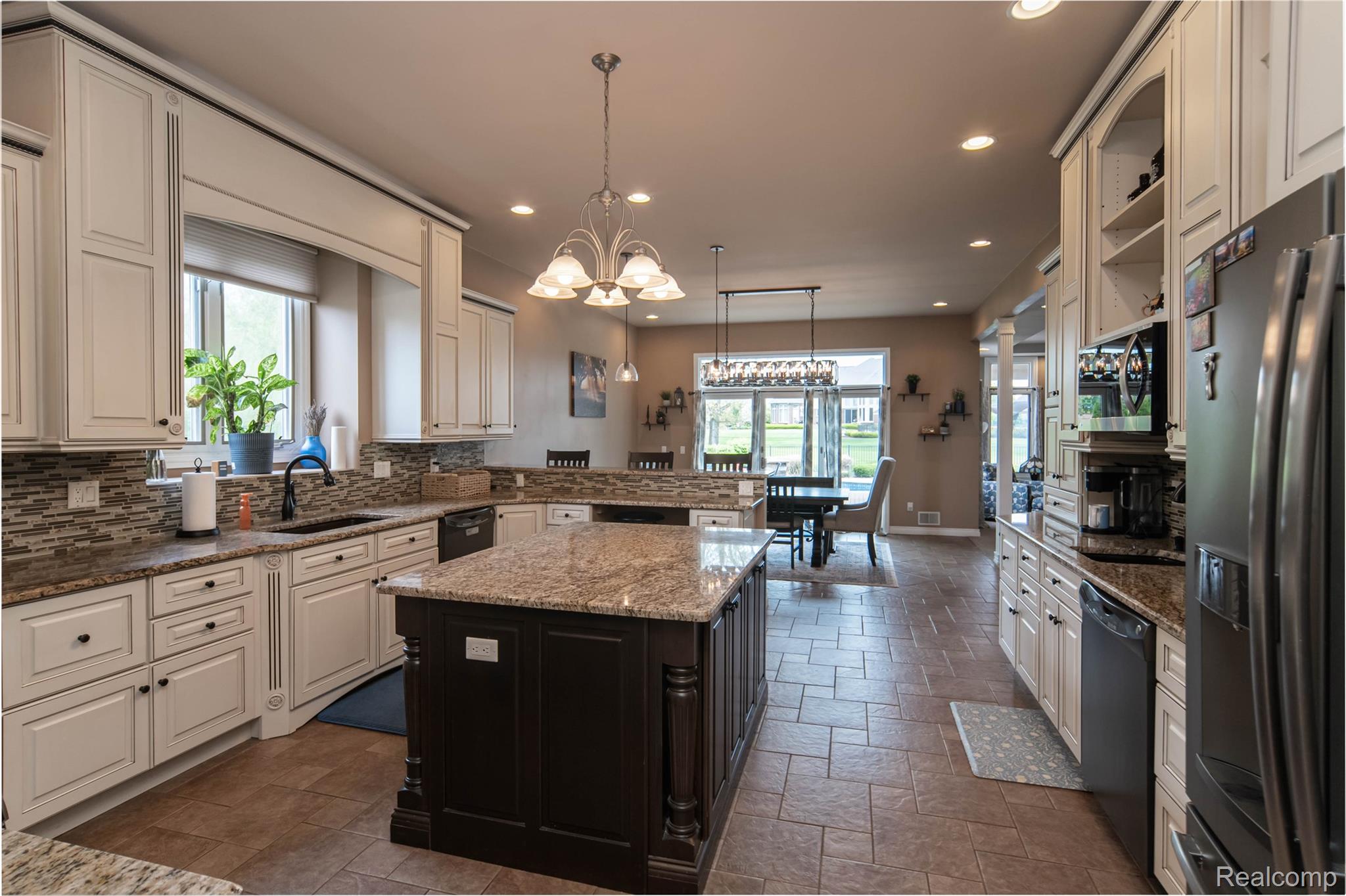 67102 Rachael Lane Washington, MI 48095 - Photo 16 of 37 Dual tone kitchen with dual tone cabinets, stainless steel appliances, dark stone countertops, suspended lighting, and a center island