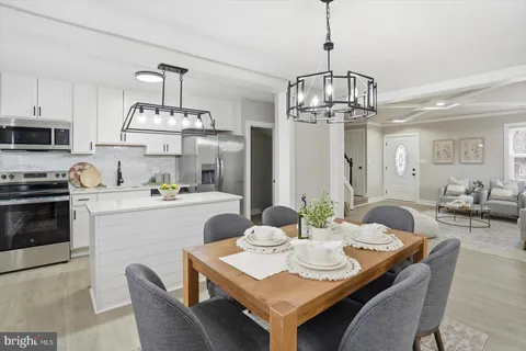 a view of a dining room with furniture a chandelier and kitchen view