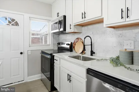 a kitchen with stainless steel appliances a sink a stove and cabinets