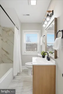 a bathroom with a granite countertop sink toilet a large mirror a vanity and bathtub