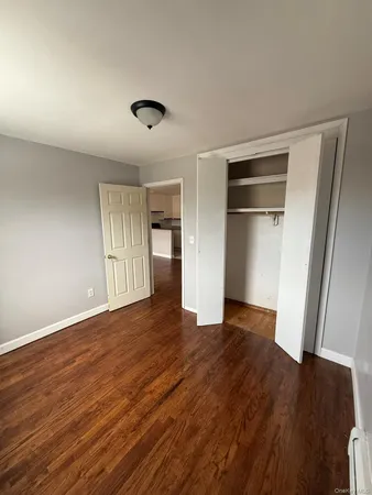 a view of an empty room with wooden floor and closet