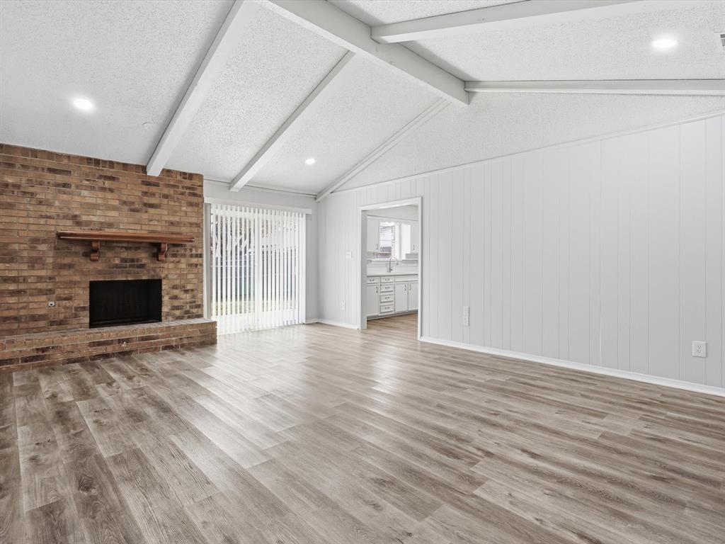 625 Reno Street Lewisville, TX 75077 - Photo 12 of 25 an empty room with wooden floor and fireplace