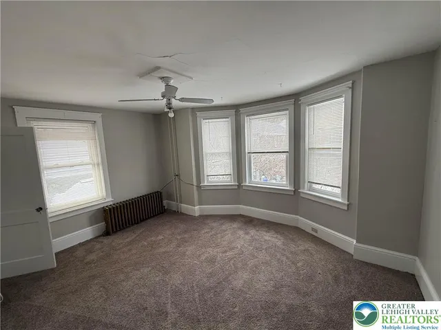 an empty room with windows and chandelier fan