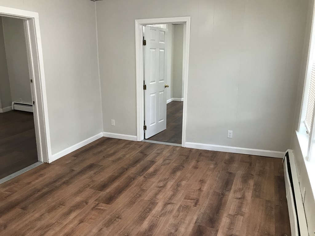 187 Mammoth Road Lowell, MA 01854 - Photo 3 of 8 an empty room with wooden floor and windows