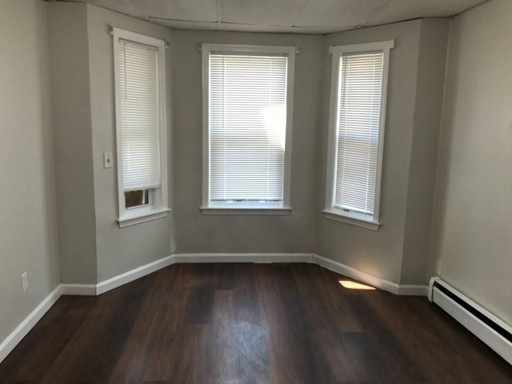 187 Mammoth Road Lowell, MA 01854 - Photo 4 of 8 a view of an empty room with wooden floor and a window