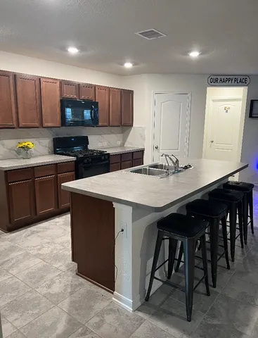 a kitchen with stainless steel appliances granite countertop a table chairs sink and white cabinets