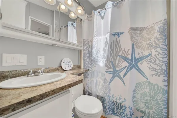a bathroom with a granite countertop sink a toilet and a mirror