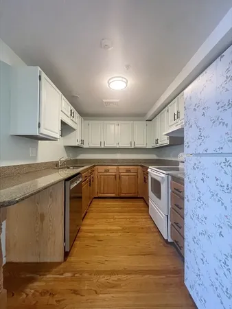 a large white kitchen with stainless steel appliances granite countertop a stove and a sink