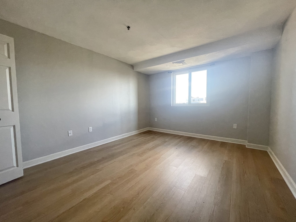 39 Parlin Street, Unit 404 Everett, MA 02149 - Photo 16 of 25 an empty room with wooden floor and windows