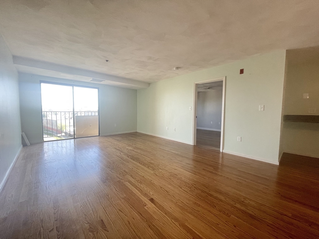 39 Parlin Street, Unit 404 Everett, MA 02149 - Photo 9 of 25 an empty room with wooden floor and windows