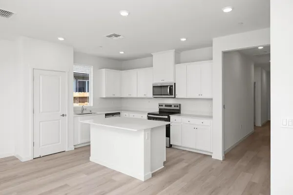 a kitchen with stainless steel appliances cabinets a sink and wooden floor