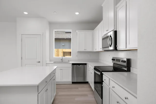 a kitchen with stainless steel appliances granite countertop a sink and dishwasher a stove top oven with white cabinets