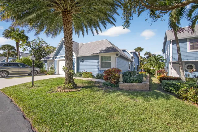 a view of a house with a yard and palm trees