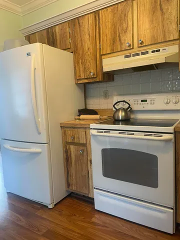 a white refrigerator freezer sitting inside of a kitchen with stainless steel appliances wooden floor and a refrigerator