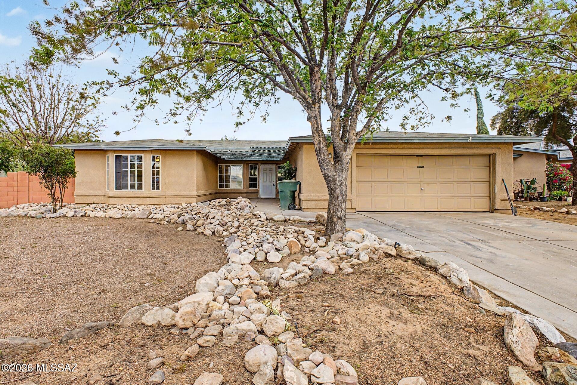 9810 East Stonehaven Way Tucson, AZ 85747 - Photo 1 of 27 a front view of a house with a yard and garage