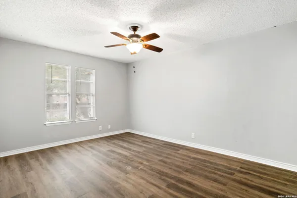 an empty room with wooden floor fan and windows