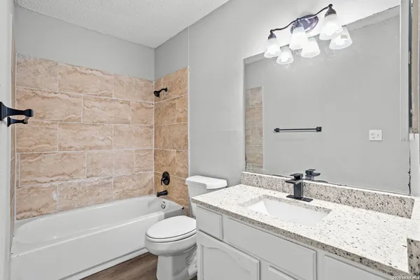 a bathroom with a granite countertop sink a toilet and bathtub