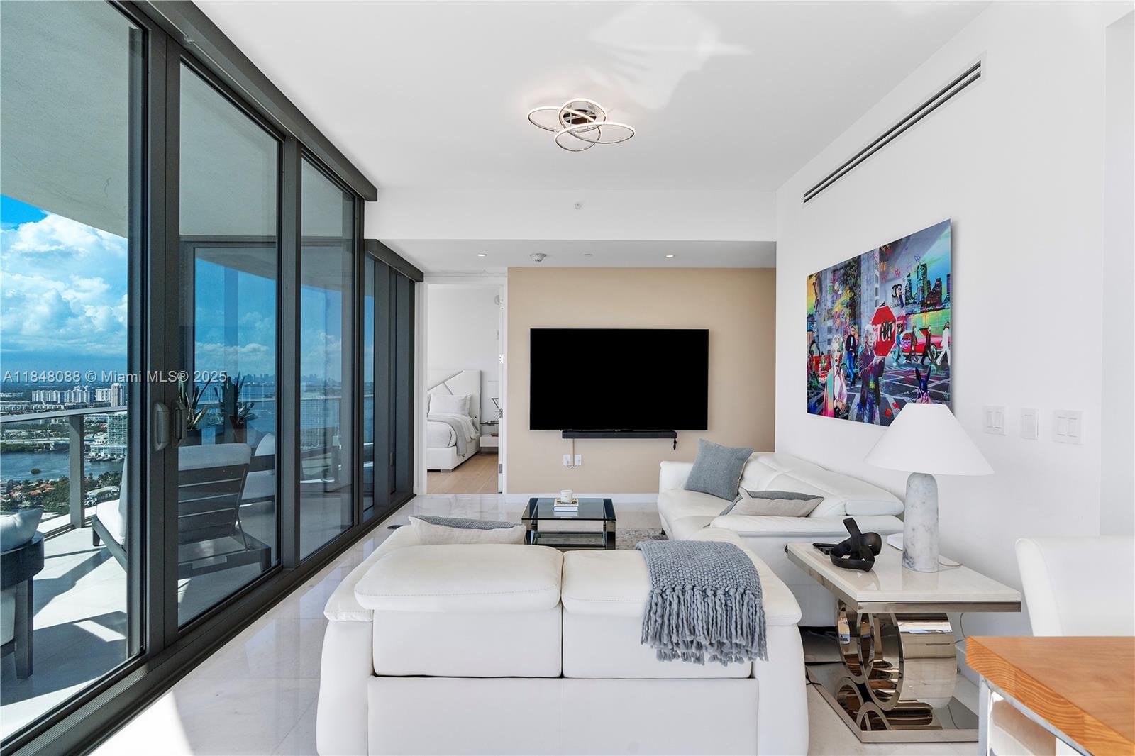 15701 Collins Avenue, Unit 3605 Sunny Isles Beach, FL 33160 - Photo 7 of 46 a living room with furniture and a flat screen tv