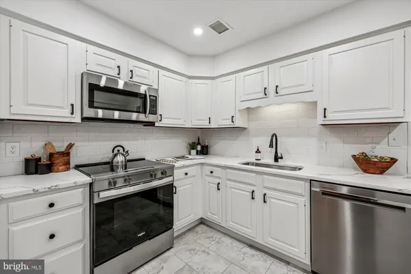 a kitchen with cabinets stainless steel appliances a sink a stove and cabinets