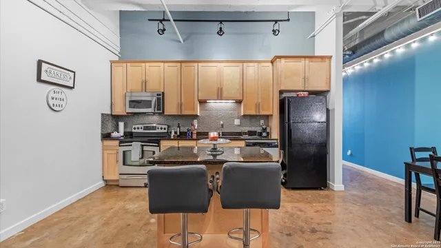 a kitchen with stainless steel appliances granite countertop a stove top oven a sink dishwasher a dining table and chairs with wooden floor