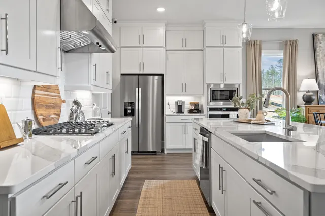 a kitchen with stainless steel appliances granite countertop a sink stove refrigerator and cabinets