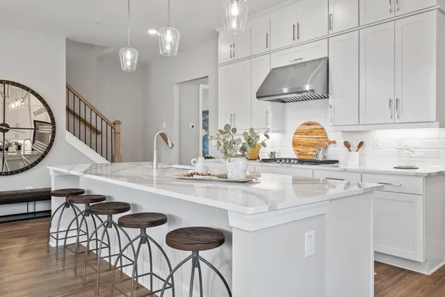 a kitchen with stainless steel appliances granite countertop a sink a stove white cabinets and chairs
