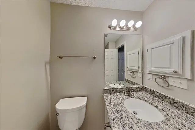 a bathroom with a granite countertop sink a toilet and a mirror