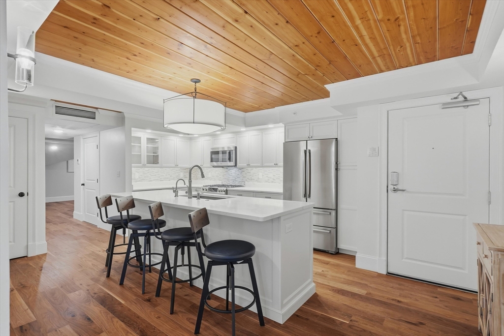 151 High Street, Unit 3B Newburyport, MA 01950 - Photo 6 of 39 a kitchen with stainless steel appliances a dining table chairs and wooden floor