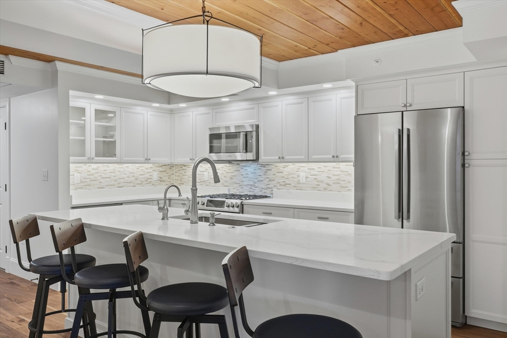 151 High Street, Unit 3B Newburyport, MA 01950 - Photo 7 of 39 a kitchen with stainless steel appliances a white table chairs and a refrigerator